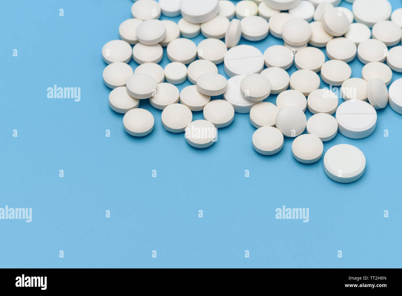 Lots of round white pills on blue background. Medication scattered on a blue background. Medical background. Health, Pharmacy, healthy lifestyle. Copy Stock Photo