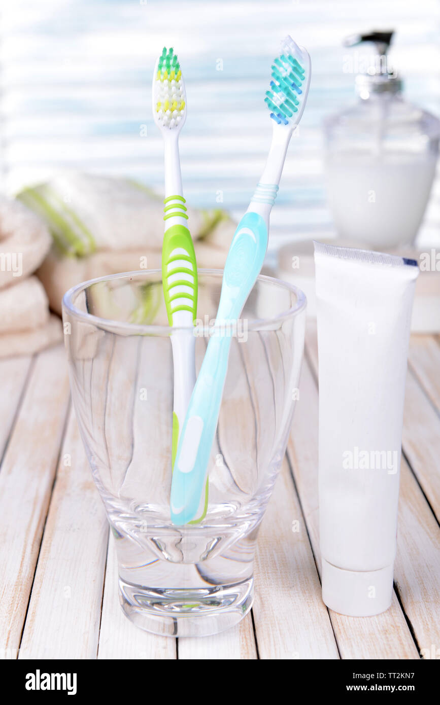 Toothbrushes in glass on table on light background Stock Photo - Alamy