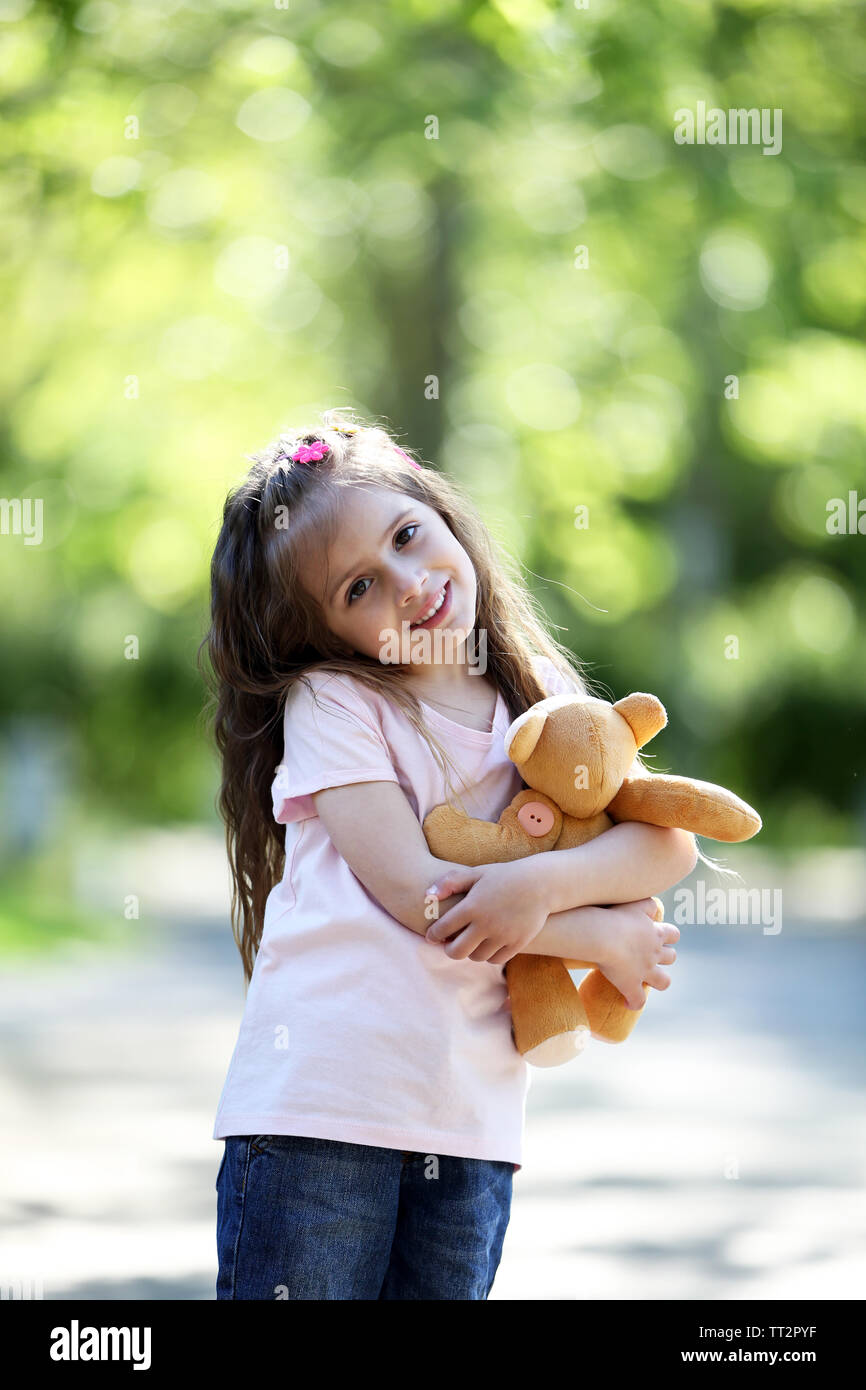 Happy little girl with toy bear in the green park Stock Photo - Alamy