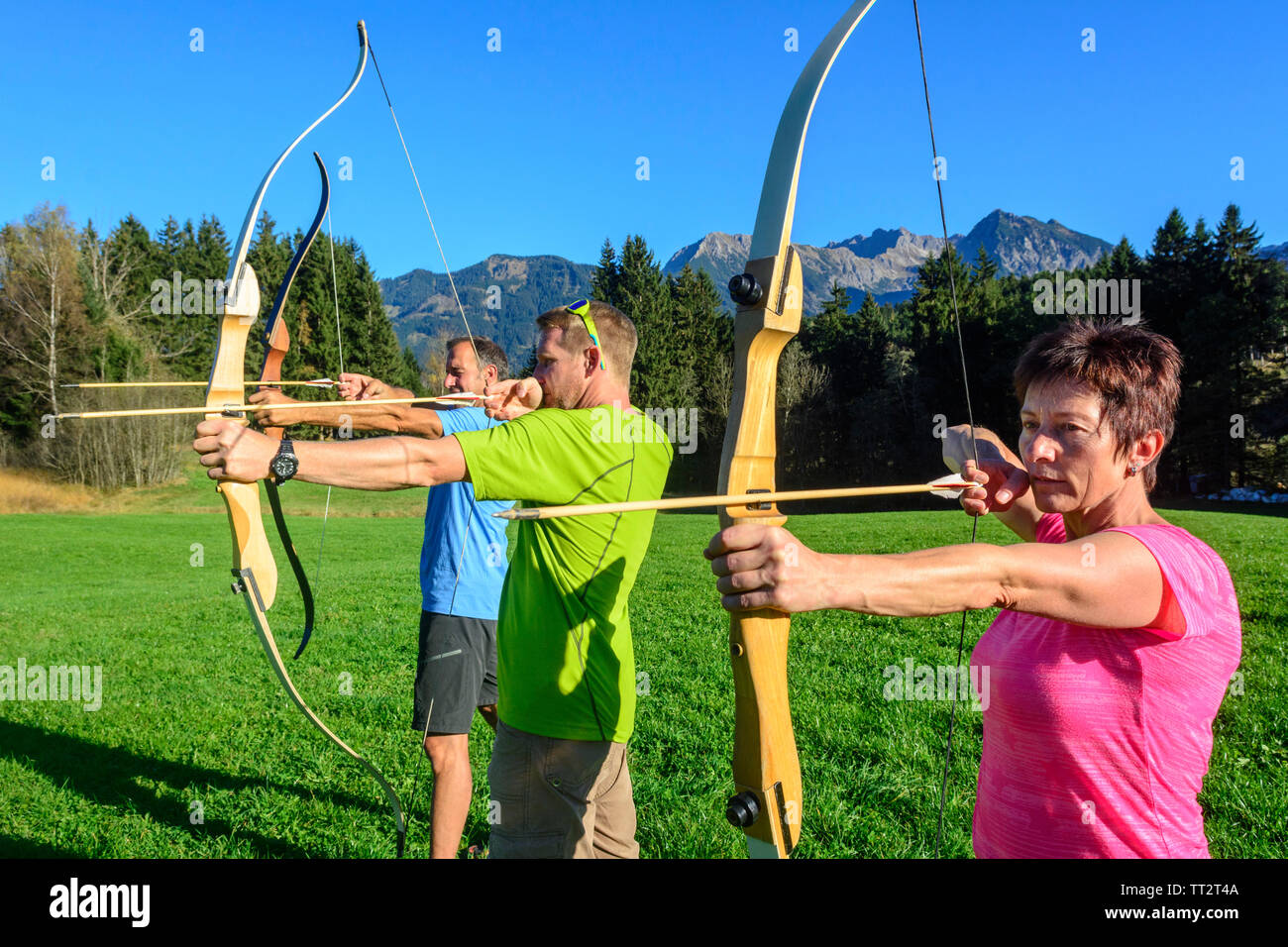 A group of adult people doing archery as an exercise during teambuilding activity Stock Photo