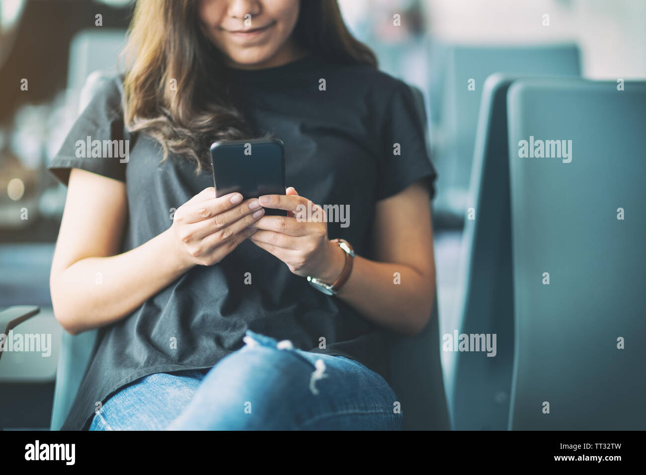 A woman traveler using mobile phone while sitting in the airport Stock Photo