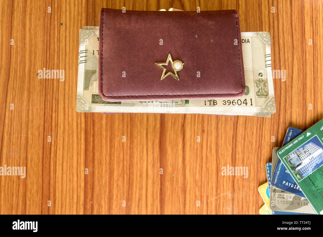 Five hundred (500) cash note in brown ladies purse and stack of credit cards on a wooden table. Business finance economy concept. High angel view with Stock Photo