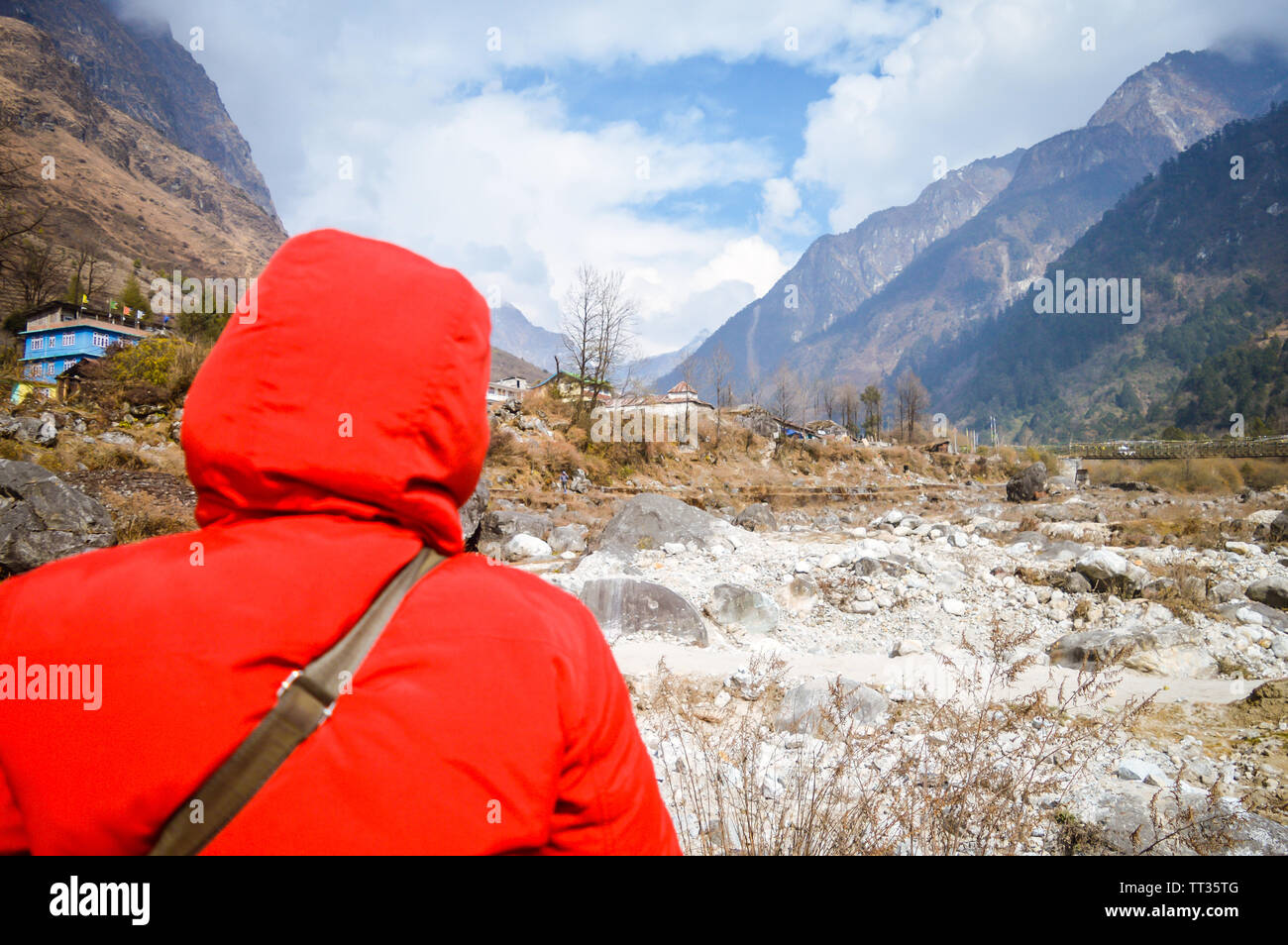 Active senior nepalese beautiful woman in red winter jacket looking at mountain and blue sky background. Relaxing moment Waiting for sunset. Enjoying Stock Photo