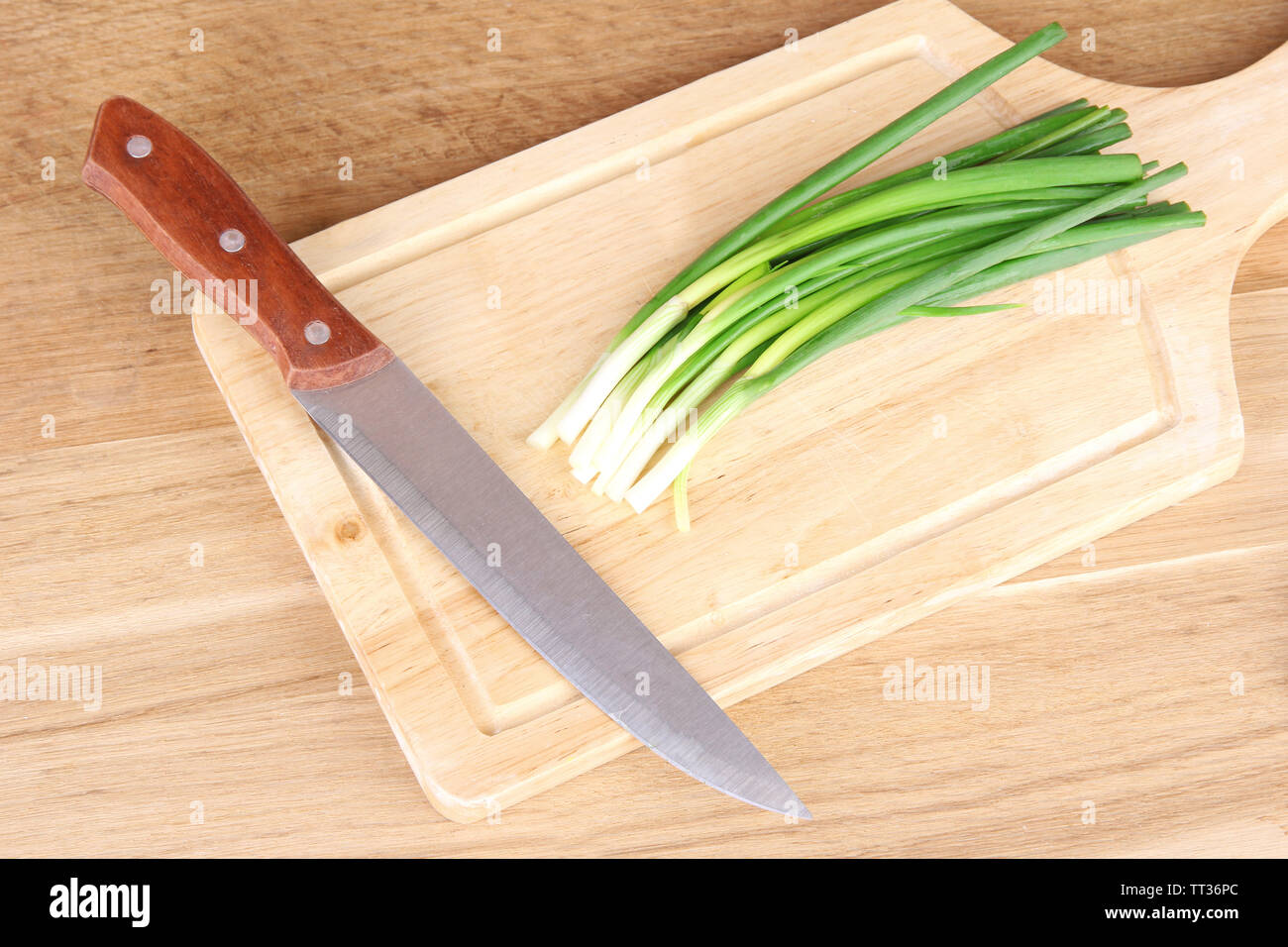 Green onion with knife on cutting board Stock Photo - Alamy