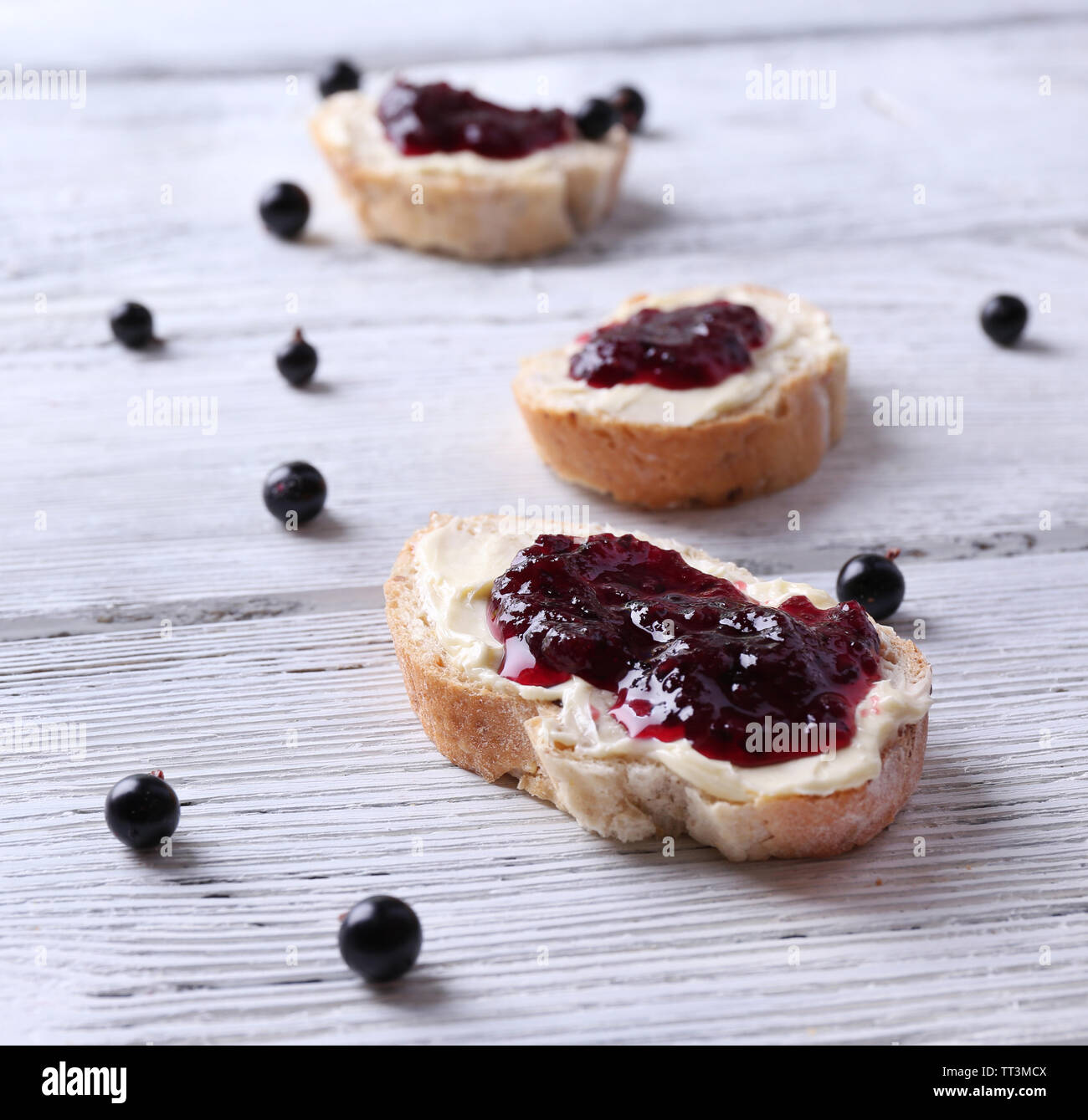 Fresh bread with homemade butter and blackcurrant jam on wooden background Stock Photo