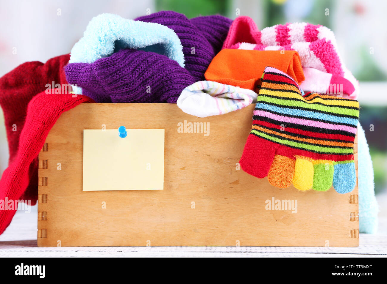 Multicoloured socks in box on a wooden table in front of the window Stock Photo