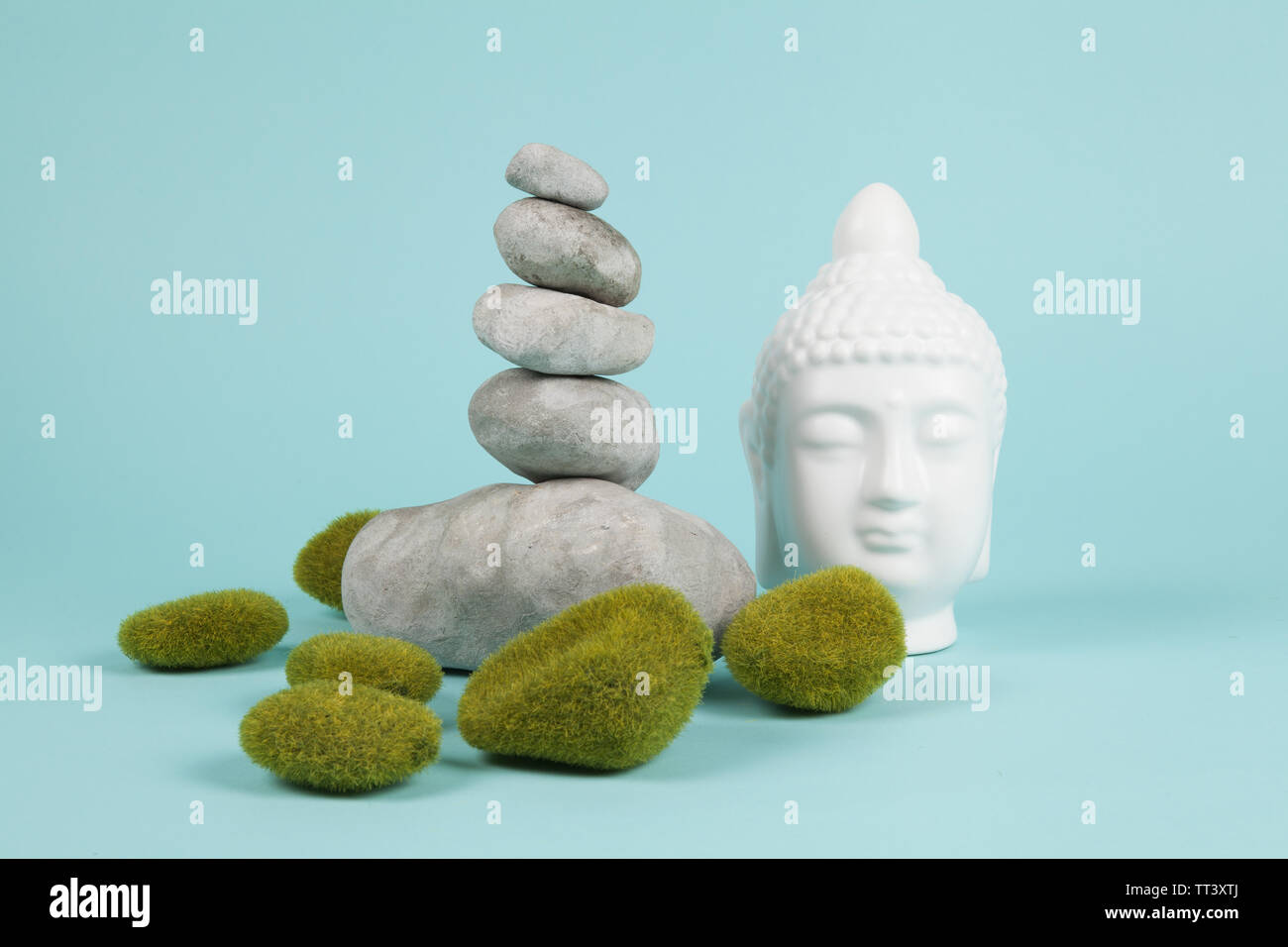 a pile of Zen stones in balance next to a Buddha's head surrounded by ...