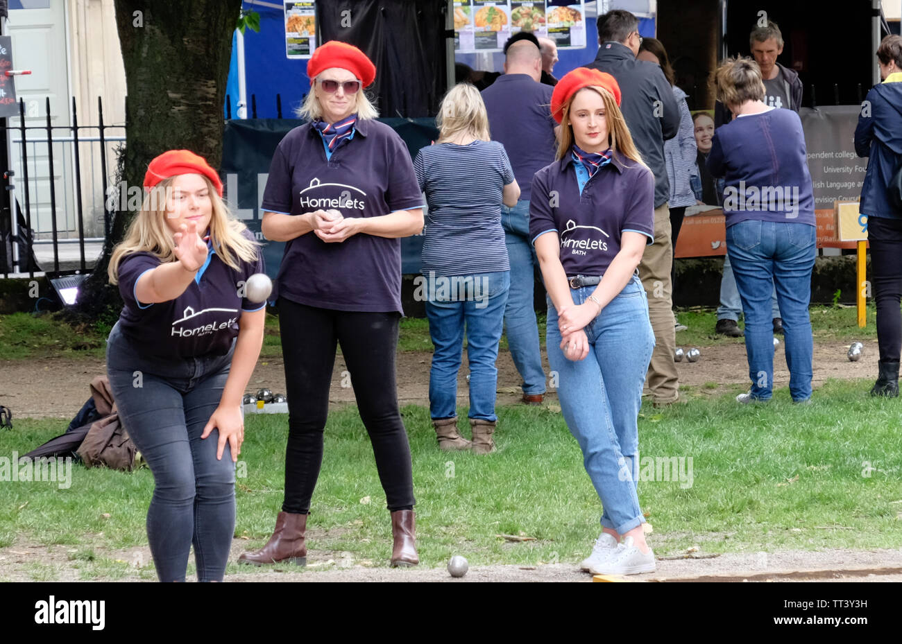 Bath, Somerset, UK. 14th June 2019. Bath Boules is a fun pop up event raising funds for local charities. The tournament takes place in Queen Square, surrounded by many stalls offering refreshments, particularly those that can be held in the left hand whilst playing boules with the right. Teams are mainly from local business’s many of whom are sponsoring the event. Credit: Mr Standfast/Alamy Live News Stock Photo