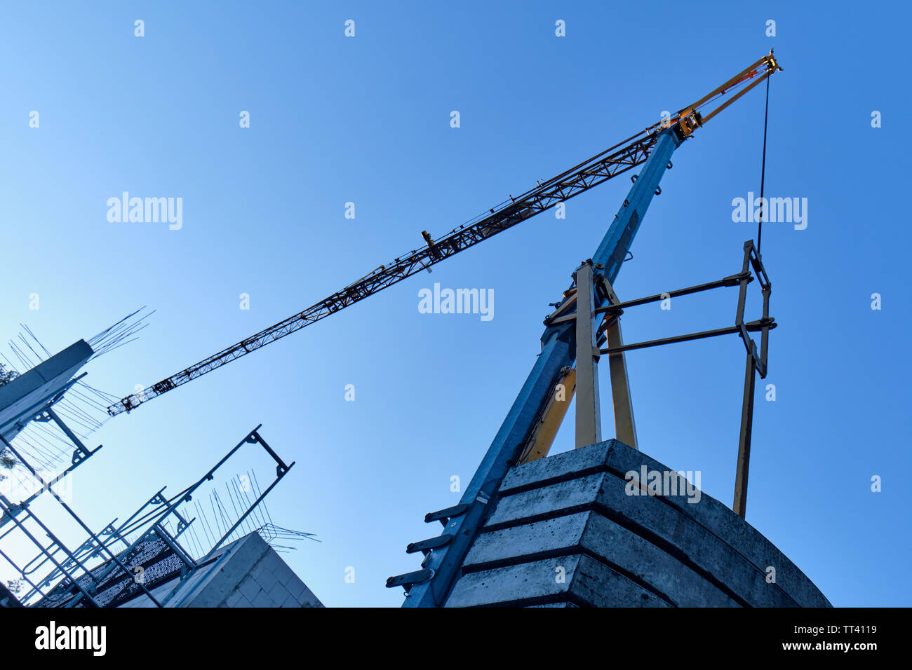 Crane against the blue sky above the shell construction of a house with a scaffolding in the evening light Stock Photo