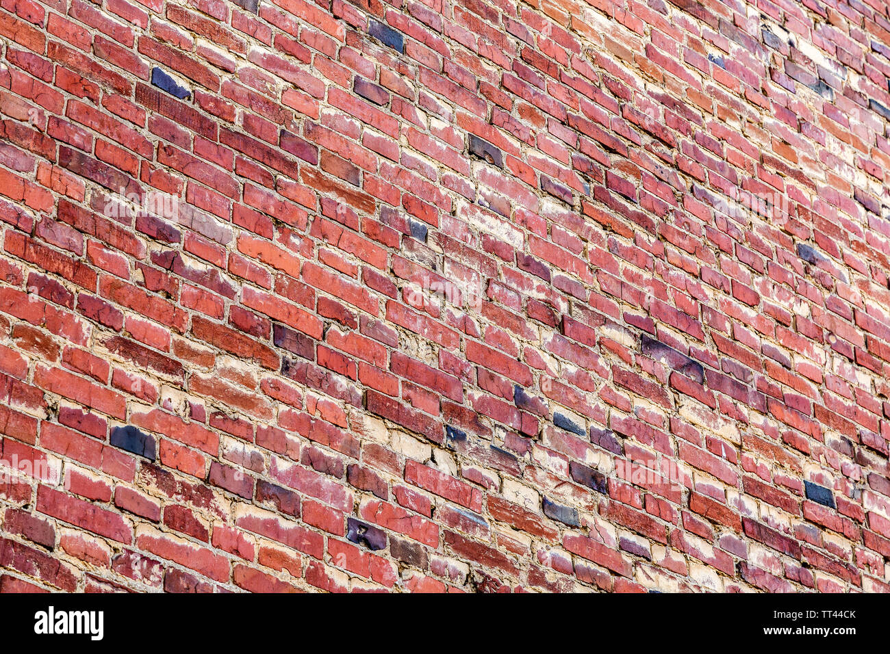 Vintage red brick wall as background texture. Bricks masonry with uneven seams. View from the angle Stock Photo