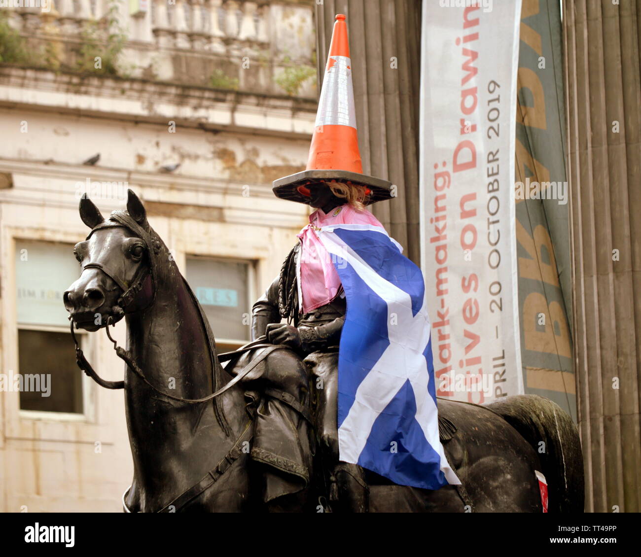Glasgow, Scotland, UK  14th June, 2019.Woman's world cup Scotland play japan and in  the city with an impromptu makeover of the iconic symbol of the city’s independent nature the cone headed man. The duke of Wellington statue outside the modern art museum, the goma, was given a blonde wig and a pink team top with a placard voicing support for the Scottish woman's team, “C’mon  Scotland” our girls our game”who play England on Sunday. Credit: Gerard Ferry/ Alamy Live News Stock Photo