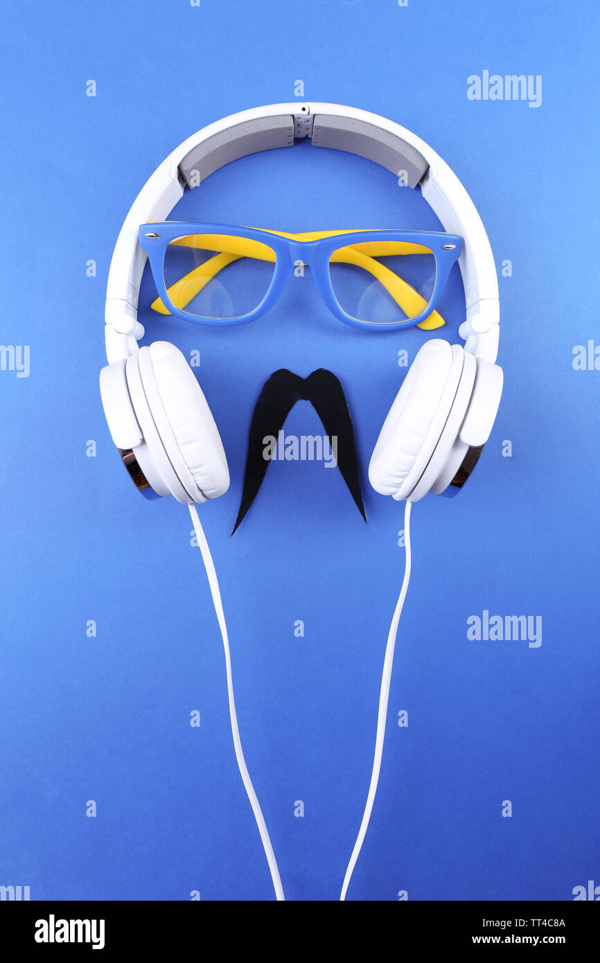 Glasses, mustache and headphone forming man face on color background