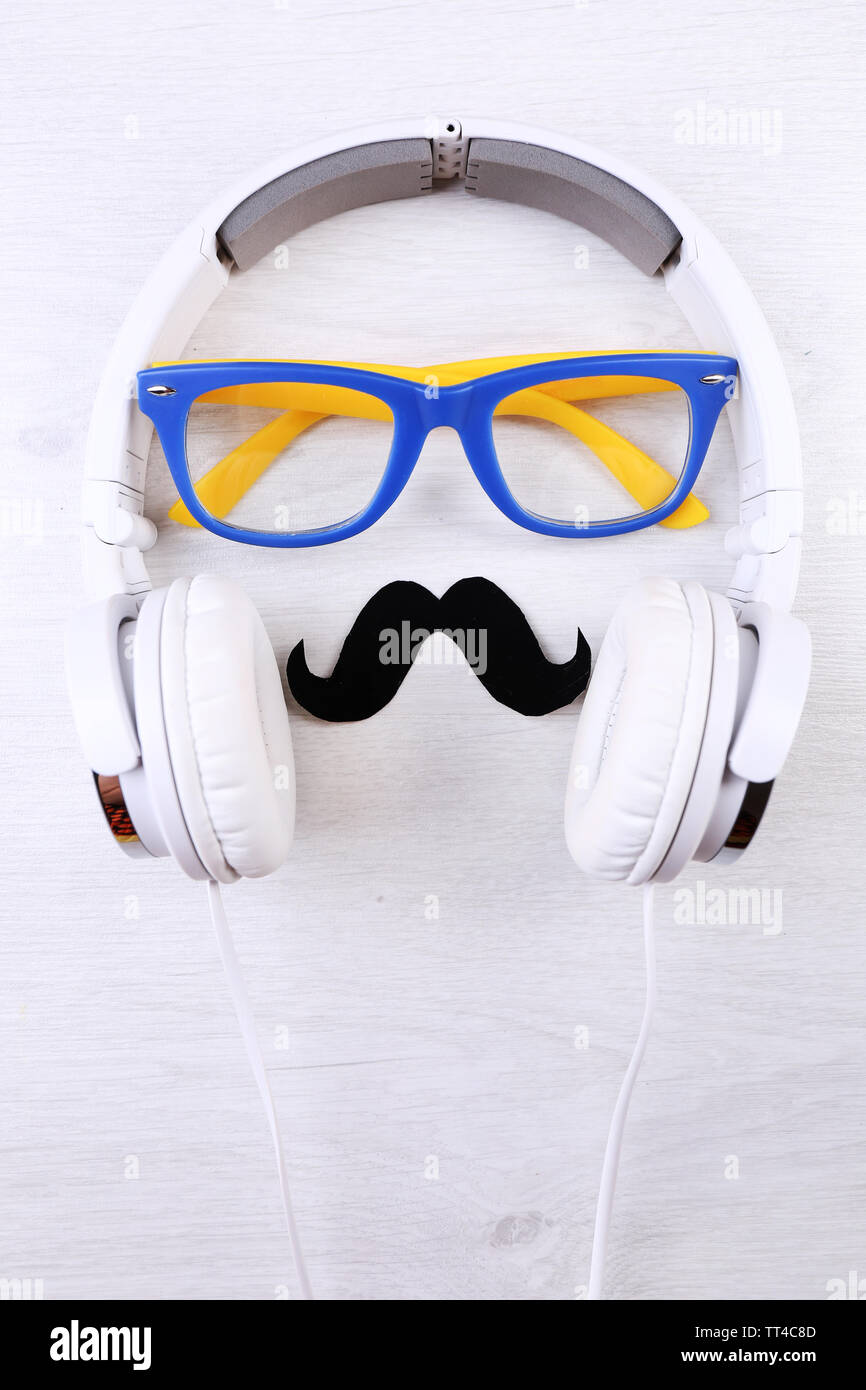 Glasses, mustache and headphone forming man face on color background