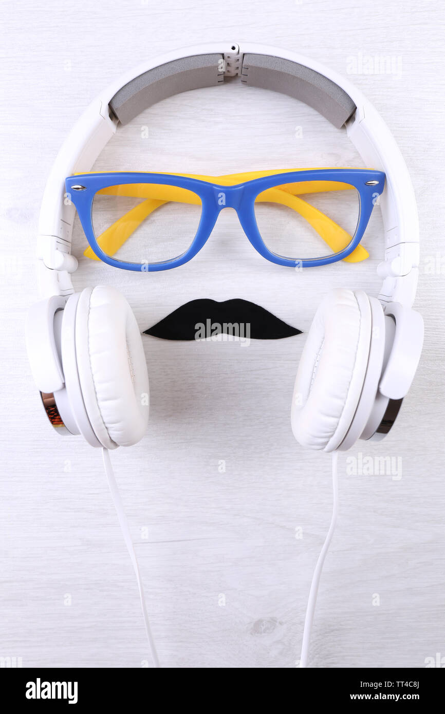 Glasses, mustache and headphone forming man face on color background