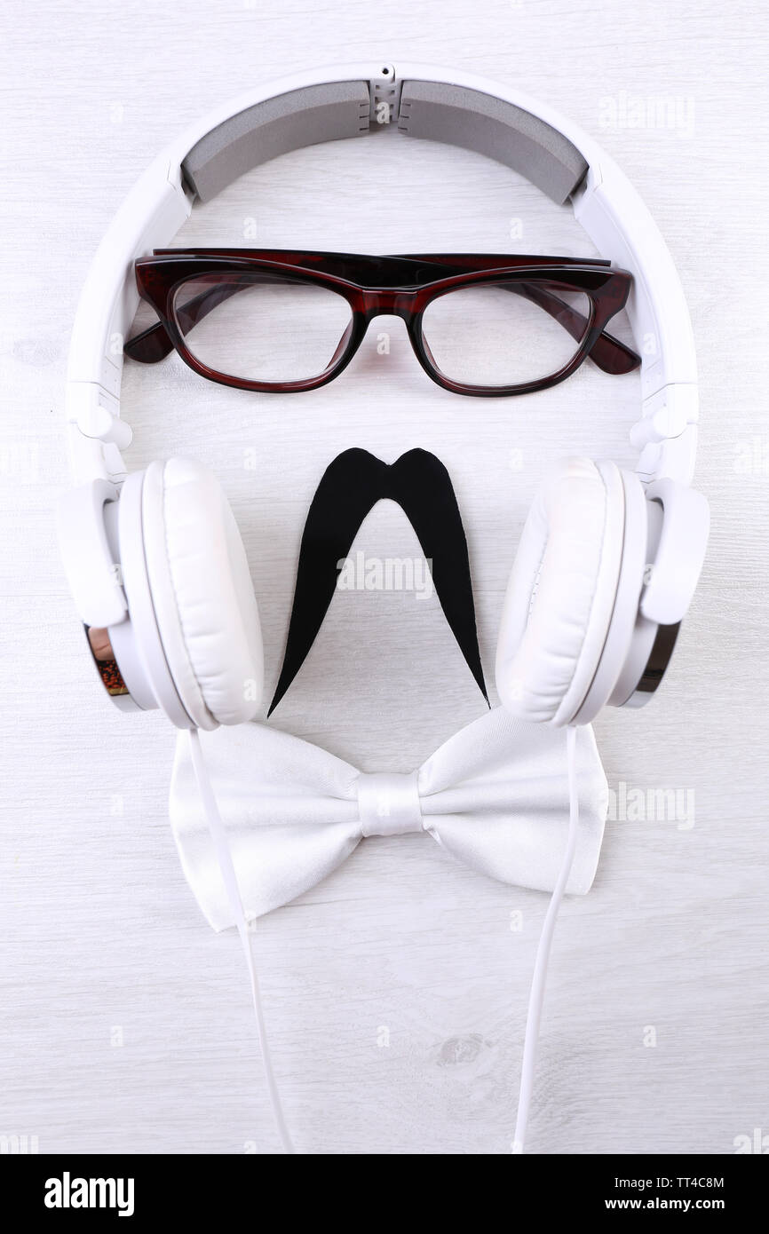 Glasses, mustache and headphone forming man face on color background