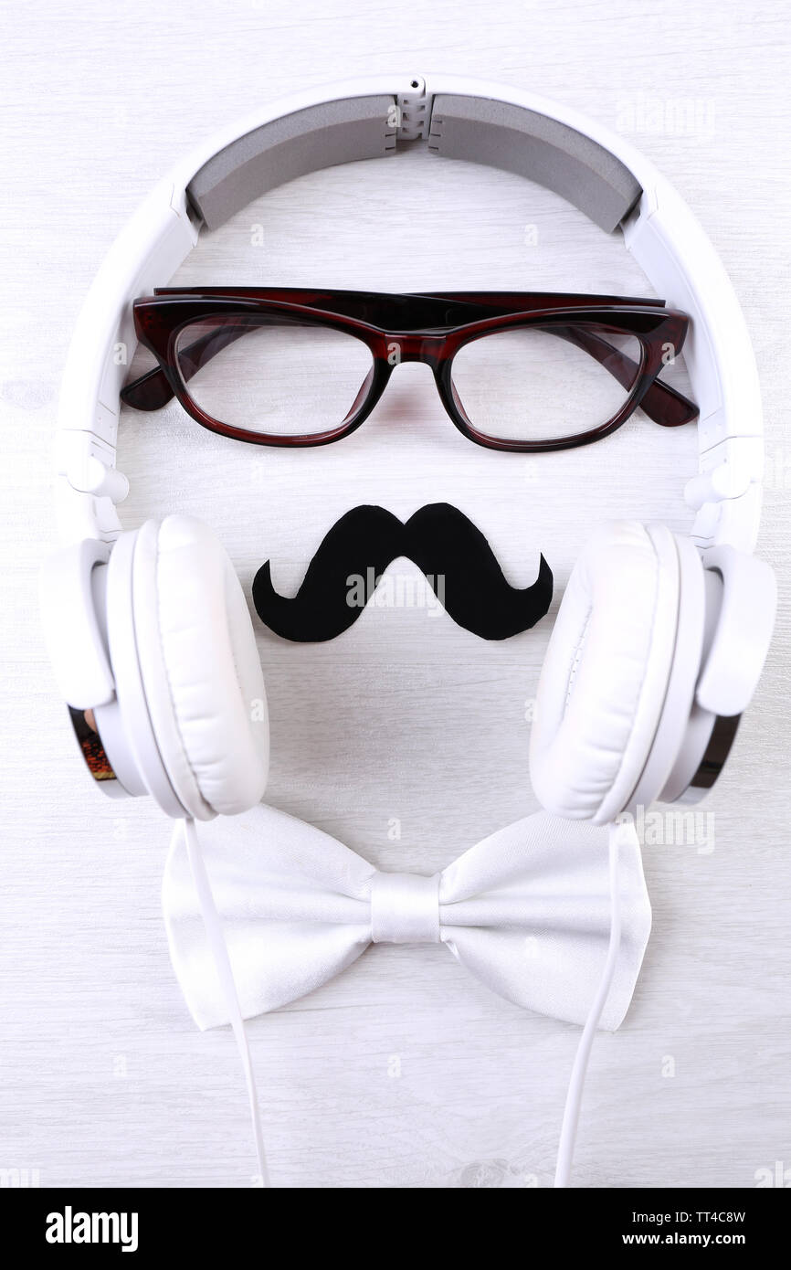 Glasses, mustache and headphone forming man face on color background