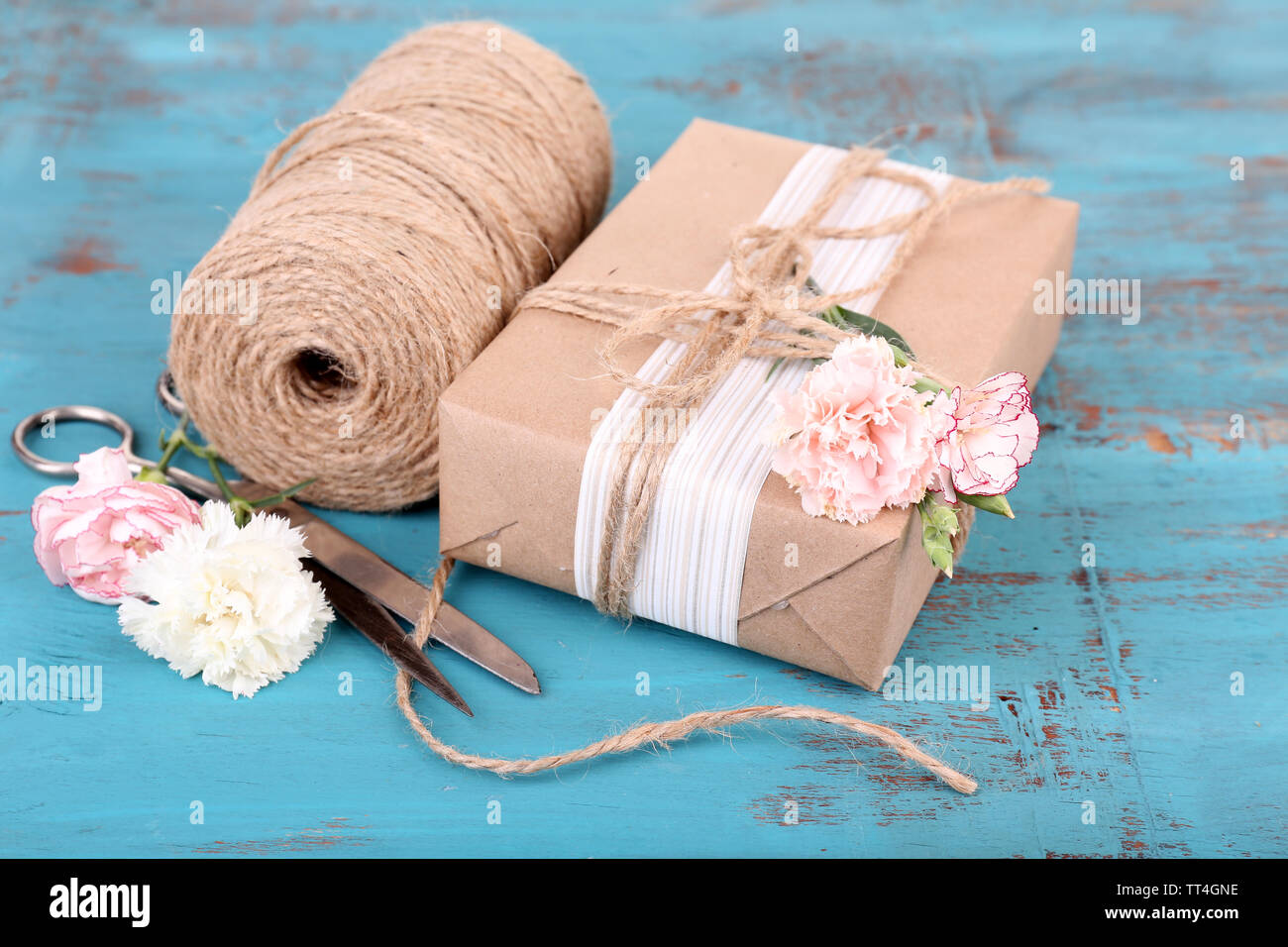 Beautiful gift with flowers and decorative rope, on old wooden ...