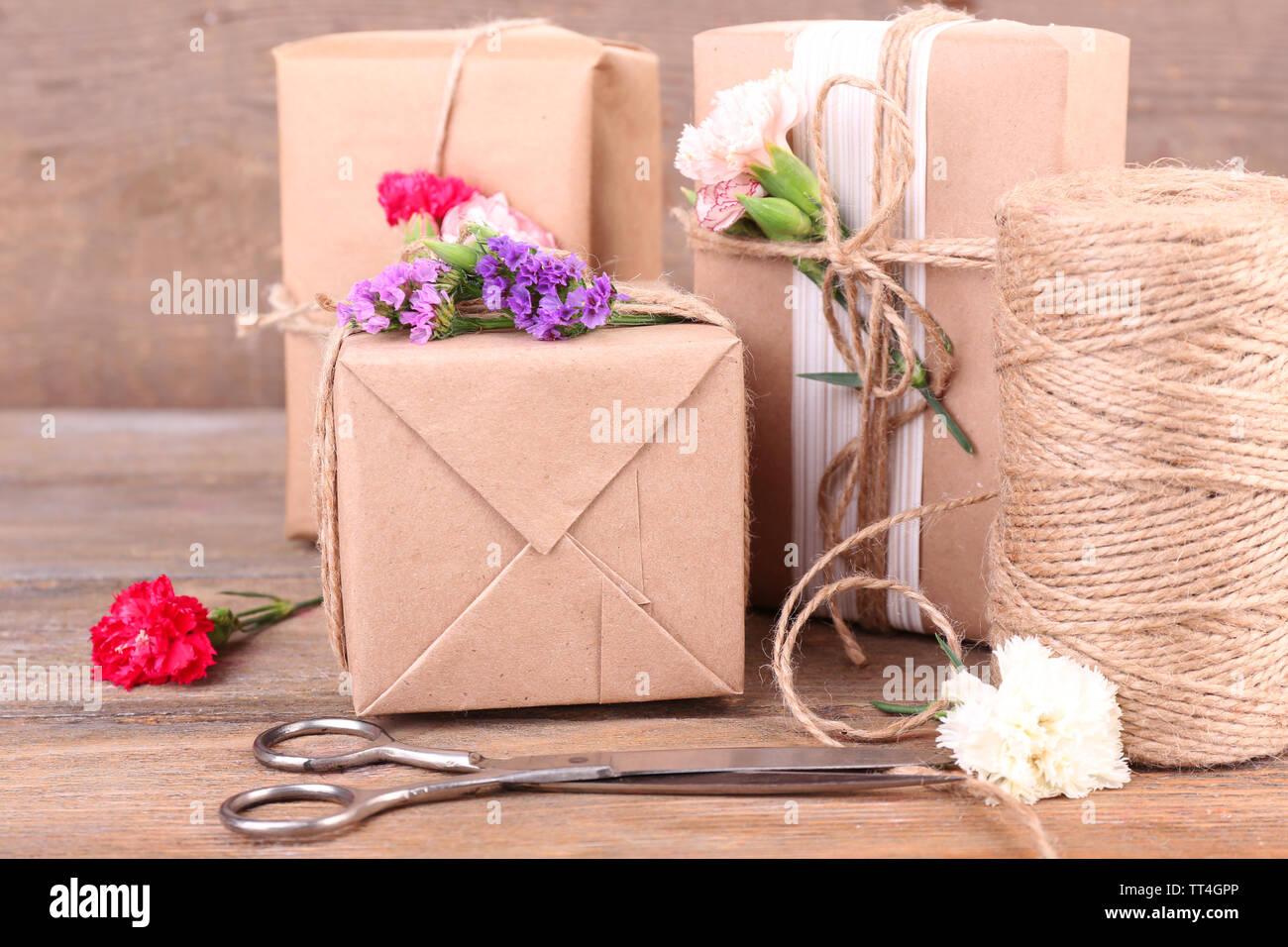 Beautiful gifts with flowers and decorative rope, on old wooden ...