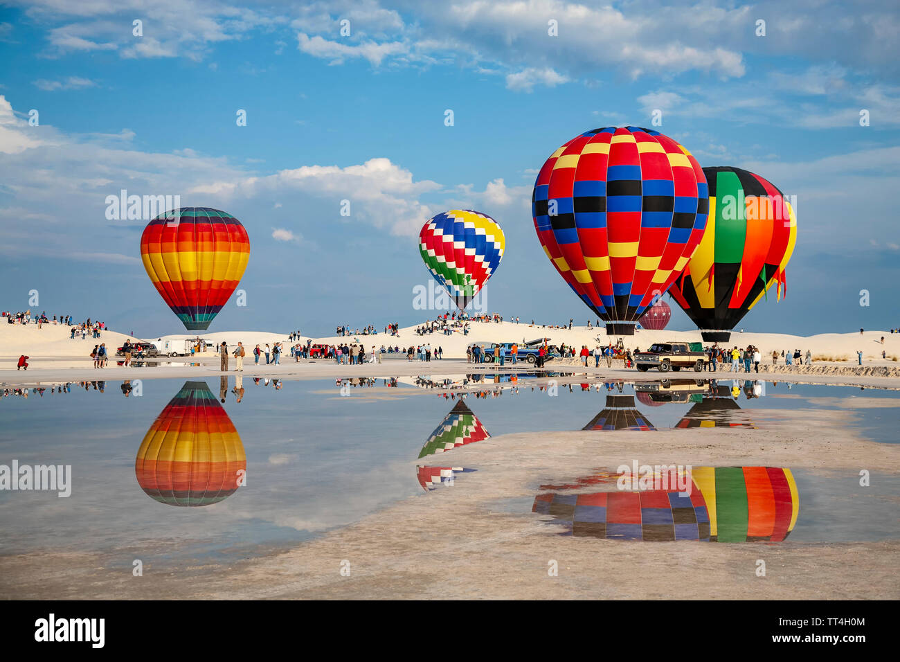 Hot air balloons reflected on puddle and people, White Sands Hot Air