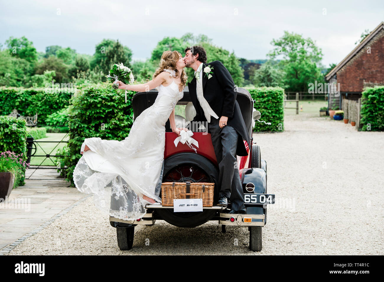 Bride and Groom kiss while standing on a Vintage Car Stock Photo - Alamy