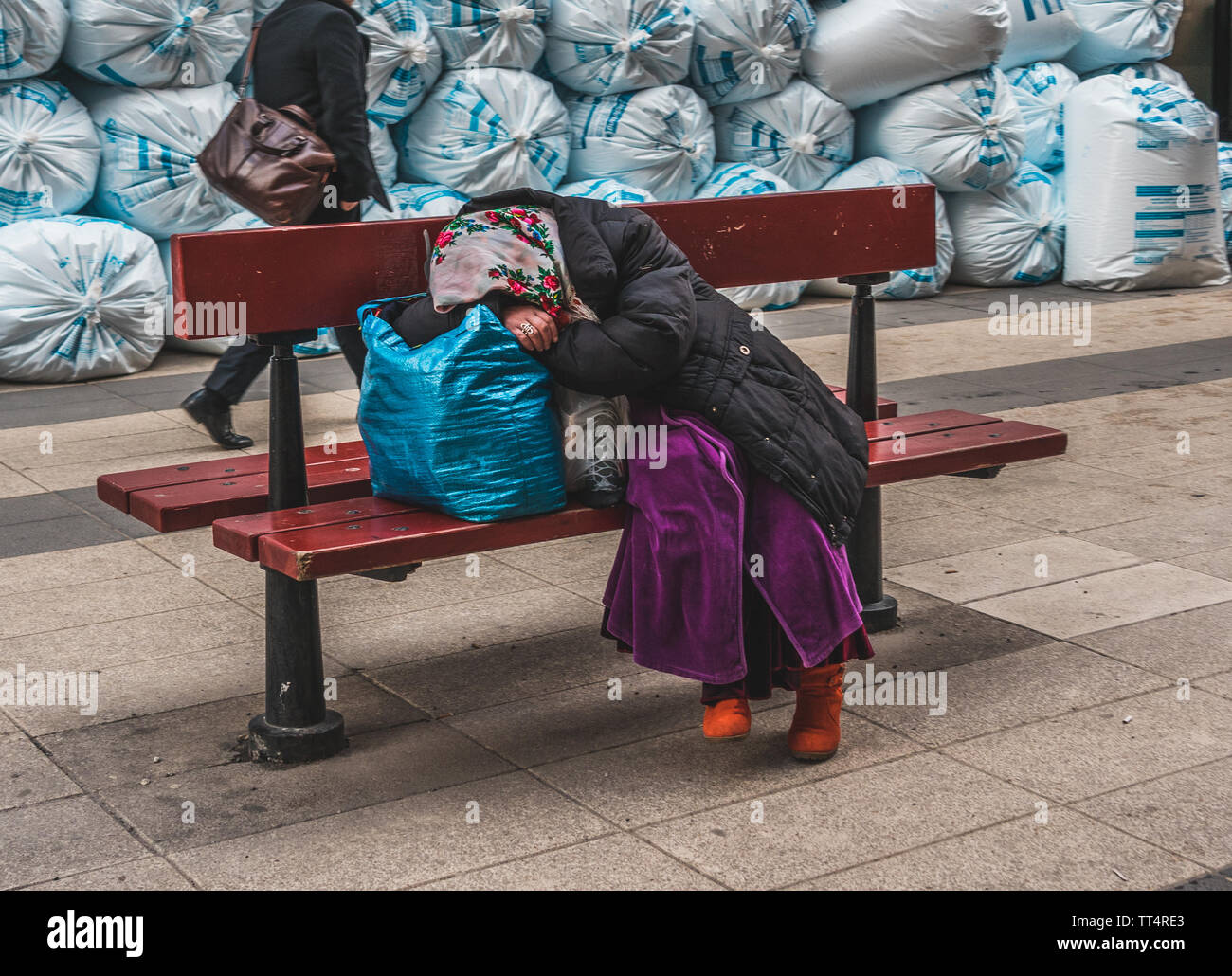 Editorial 27.03.2019 Stockholm Sweden. Romanian beggar resting on a bench with her belongings after a hard day of begging Stock Photo