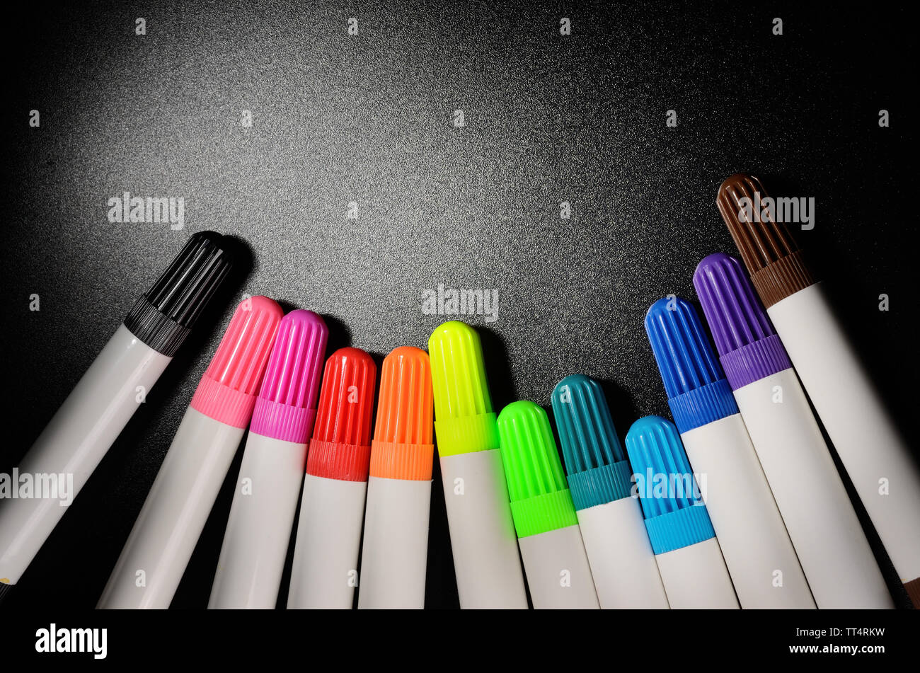 Colored felt pens on a black grained surface of the table Stock Photo