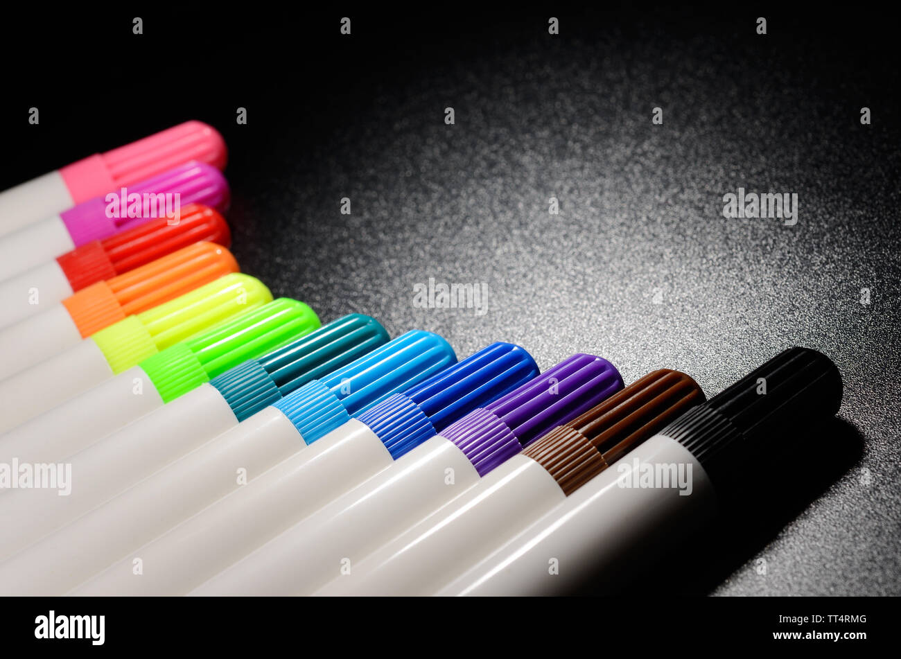 Colored felt pens on a black grained surface of the table Stock Photo