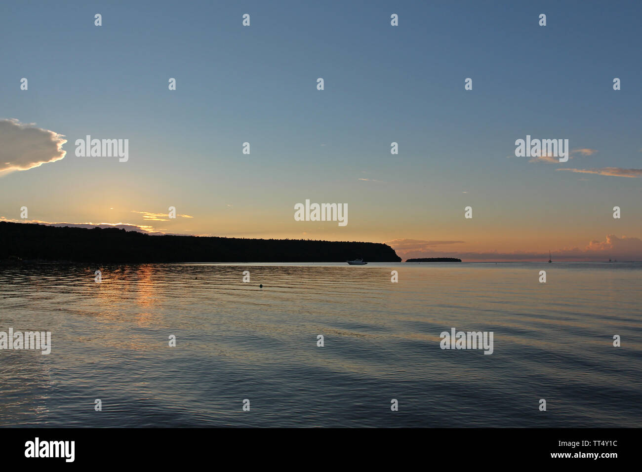 The sun setting behind a silhouetted tree line with the orange rays of
