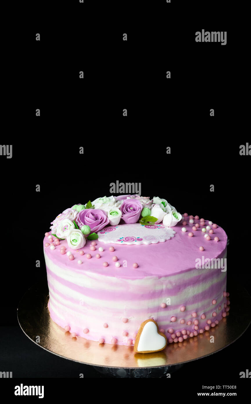 biscuit cake layered with mascarpone cream and berry cream and mastic flowers on dark Stock Photo