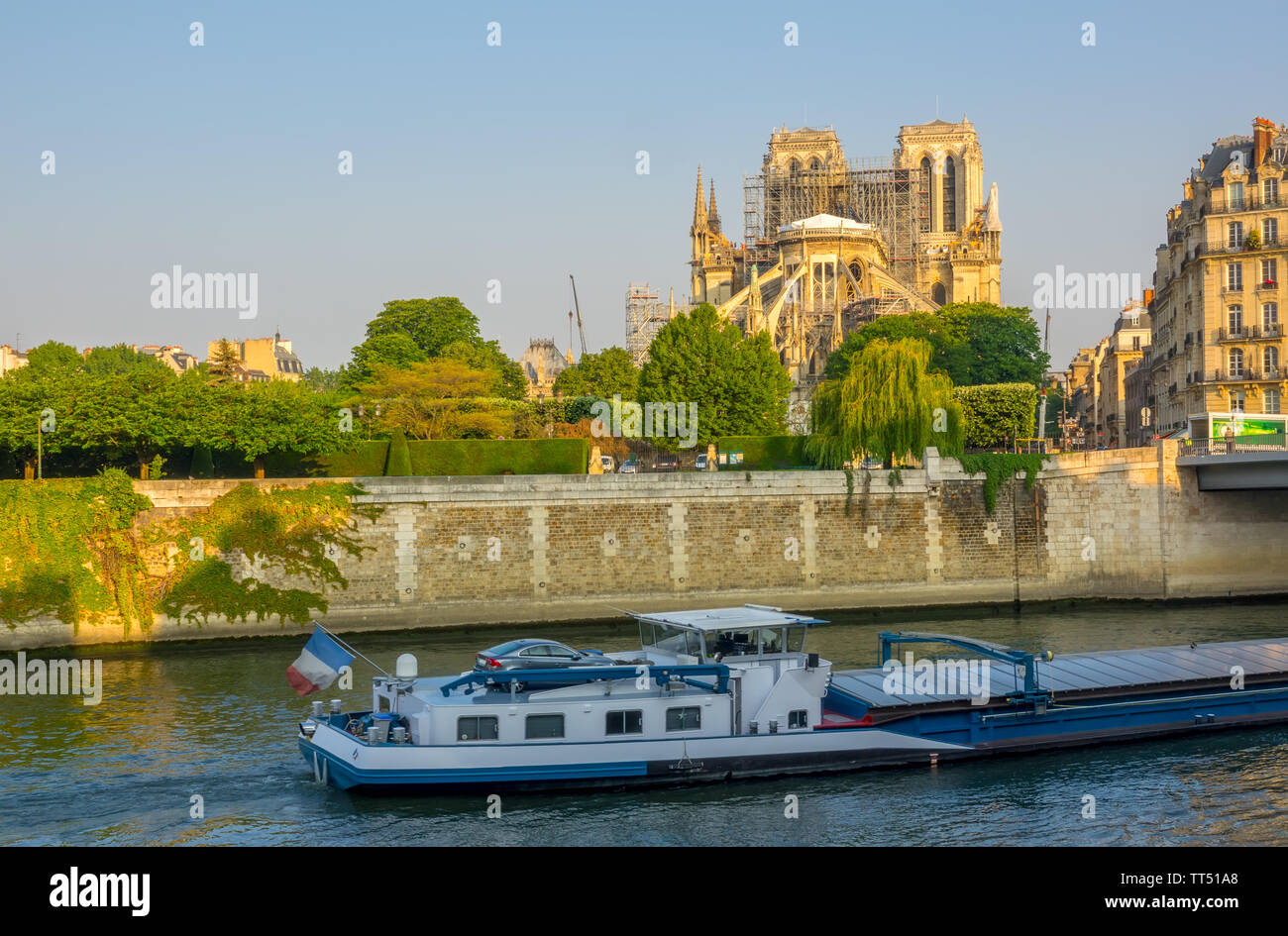 France. Paris. Sunny summer morning on the Seine embankment. View of Notre Dame in scaffolding after a fire in 2019. Barge on the river Stock Photo