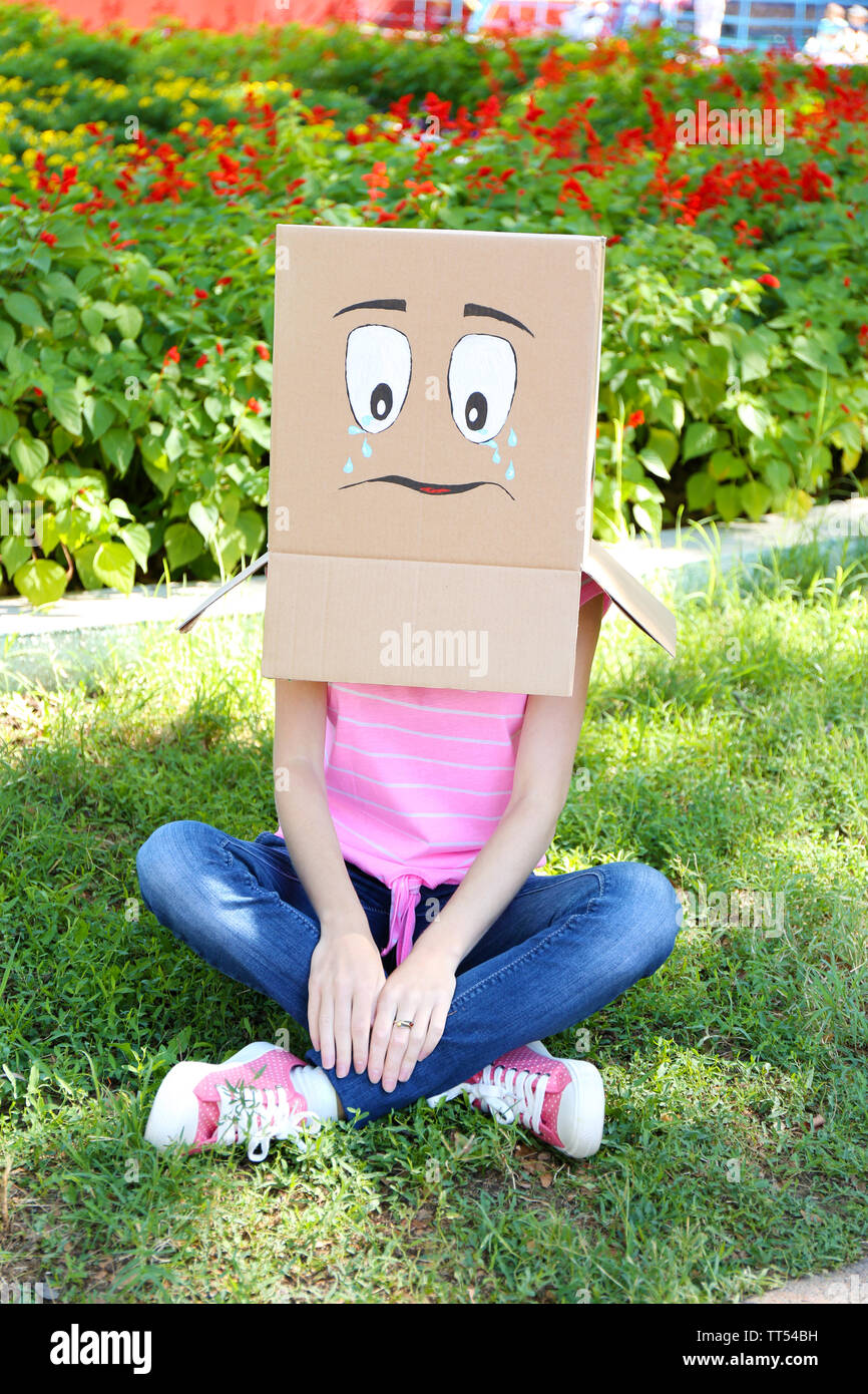 Woman with cardboard box on her head with sad face, outdoors Stock