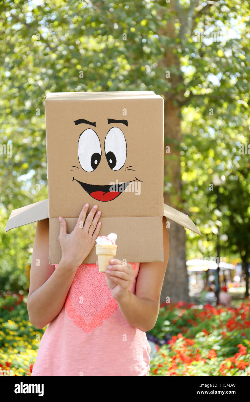 Woman with cardboard box on her head with happy face holding ice cream
