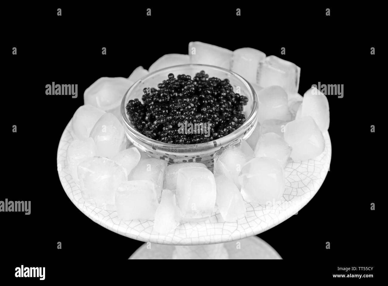 Black caviar in glass bowl and ice in plastic dish on grey background closeup Stock Photo