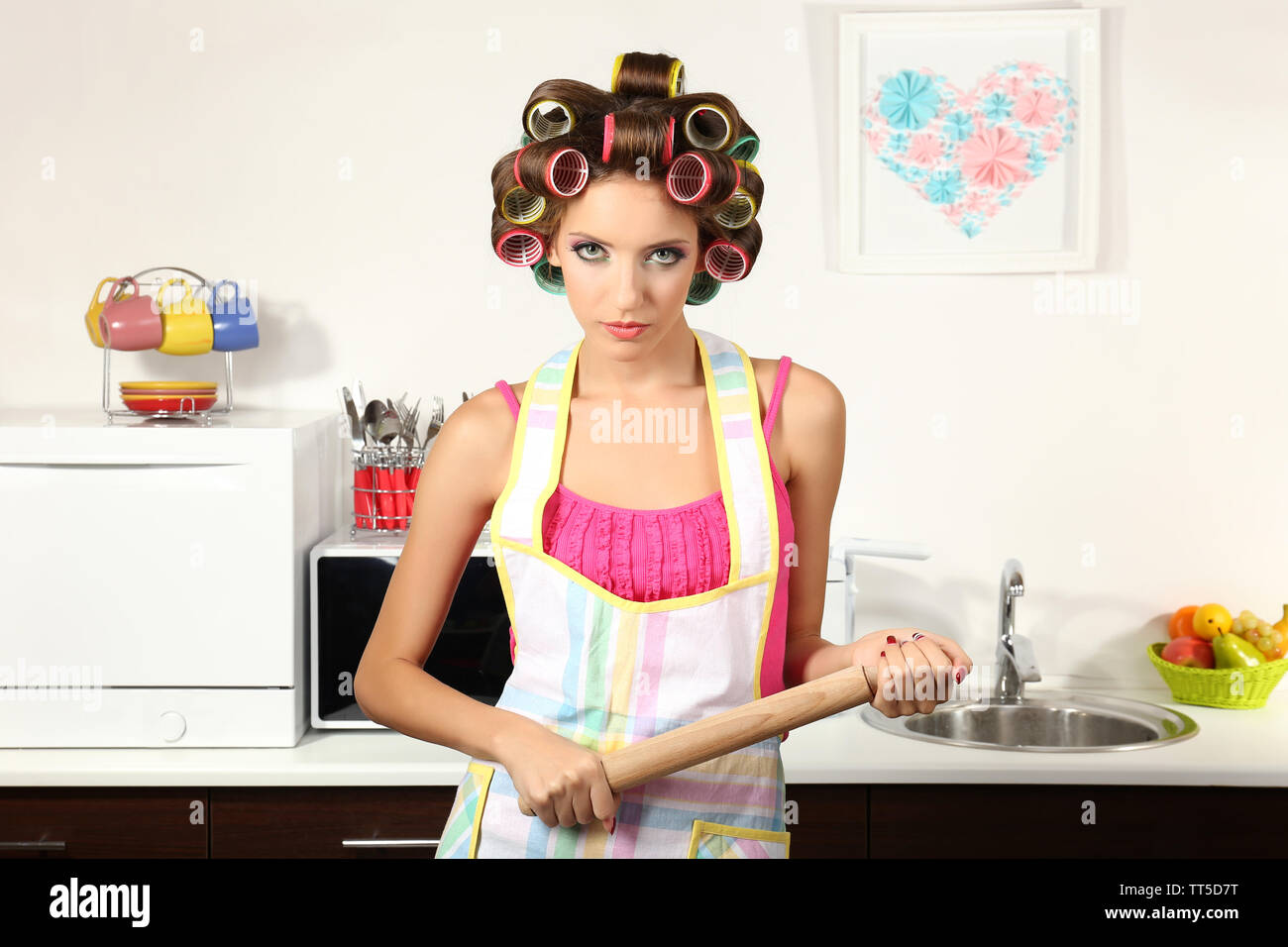 Beautiful girl in hair curlers in kitchen Stock Photo