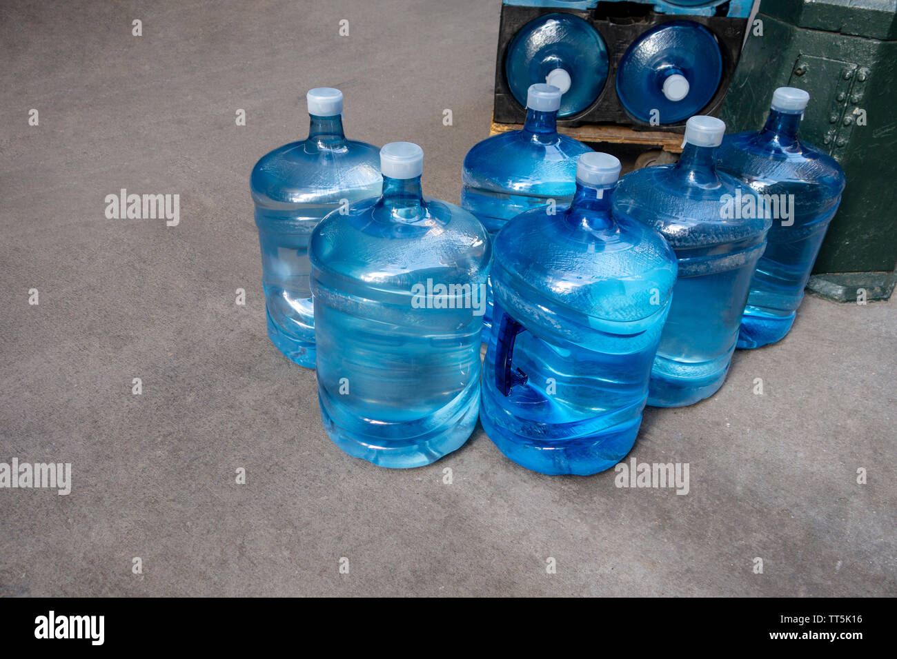 Large bottles of water on an outdoor sidewalk being delivered to and