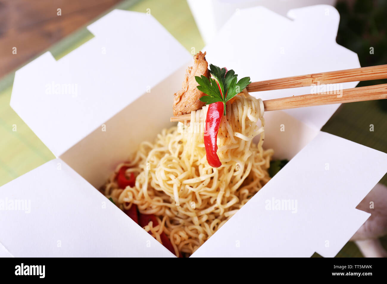 Chinese noodles and sticks in takeaway box on mat background Stock