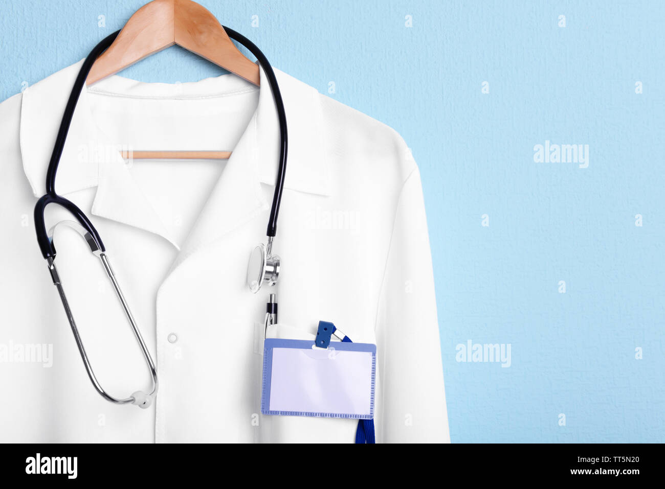Doctor coat with stethoscope on hanger on blue background Stock Photo