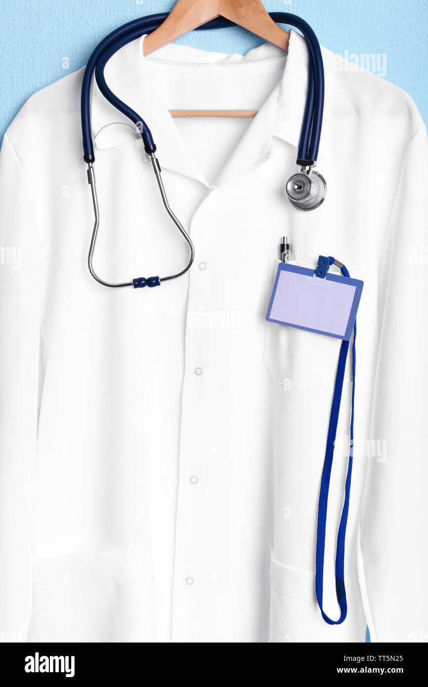 Doctor coat with stethoscope on hanger on blue background Stock Photo