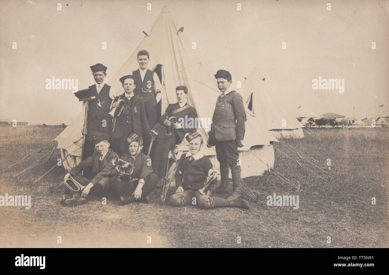 Vintage Photographic Postcard Showing What Appears To Be a Group of Boys Brigade Lads Posing Outside Their Tent With Their Bugles. Stock Photo