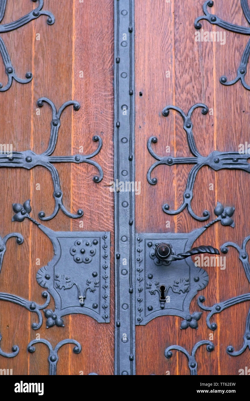 A heavy wooden church door with ornately wrought iron hinges. Stock Photo