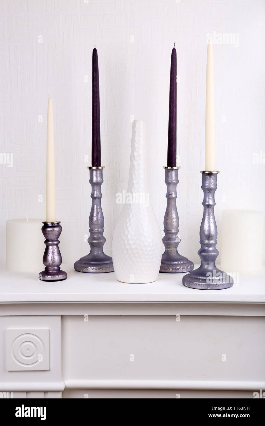 Candles in candle holders and vase on table on light background Stock Photo