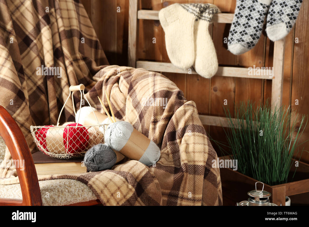 Rocking chair with plaid and yarn for knitting near wooden wall Stock ...
