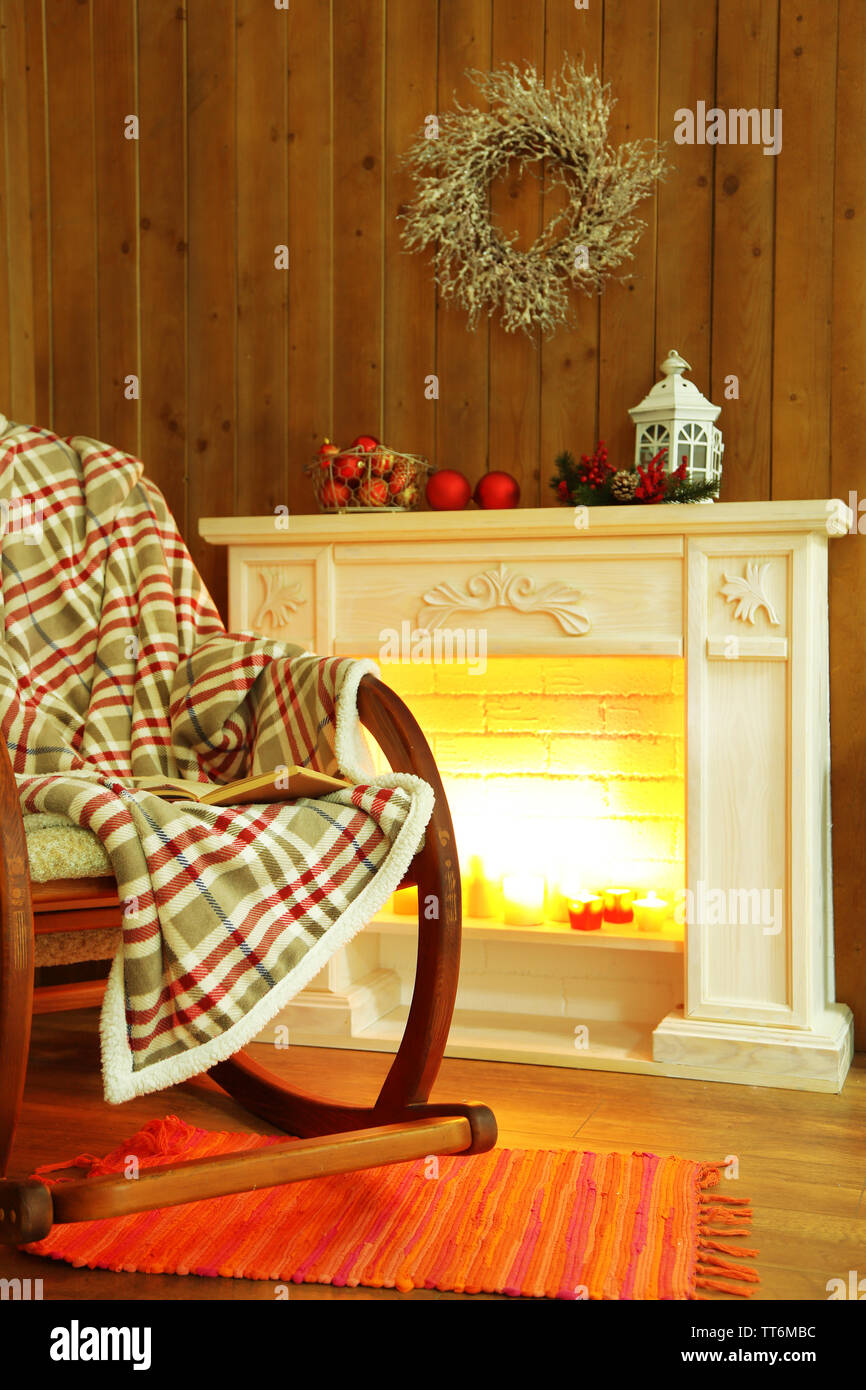 Rocking chair with plaid near fireplace Stock Photo
