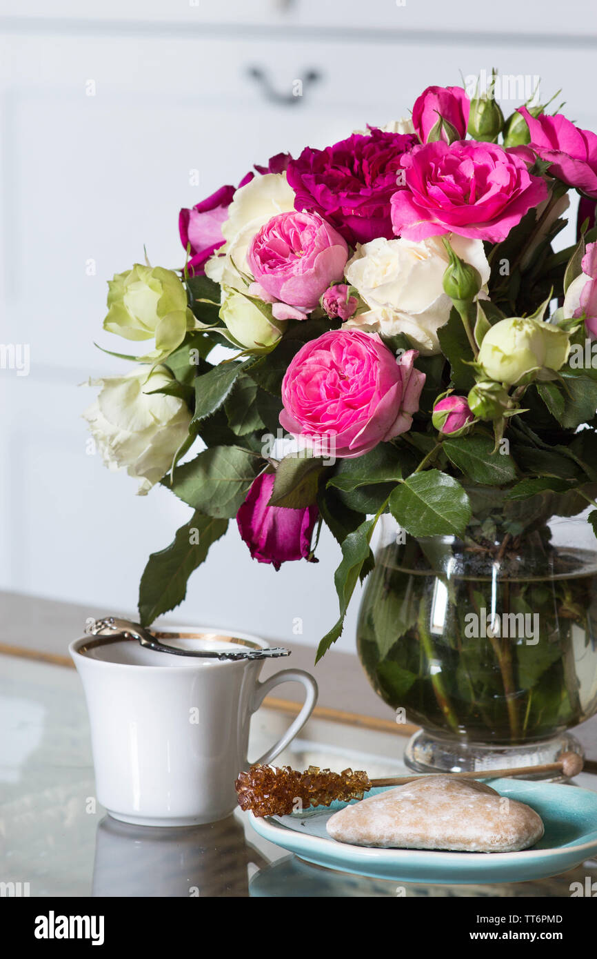 bouquet of fresh pink and white roses flowers and cup of coffee on the glass table Stock Photo