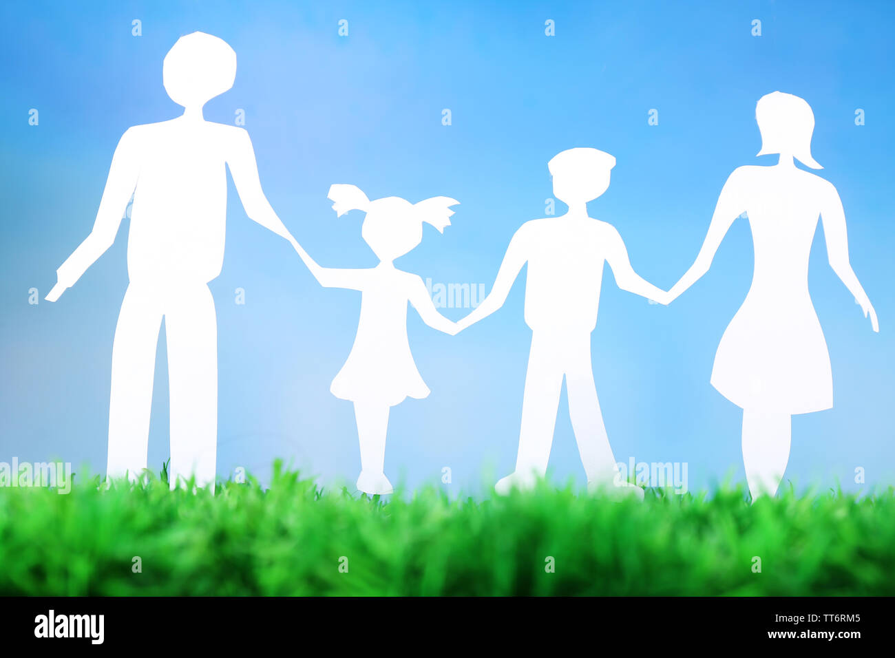 Paper family on green grass on light background Stock Photo - Alamy