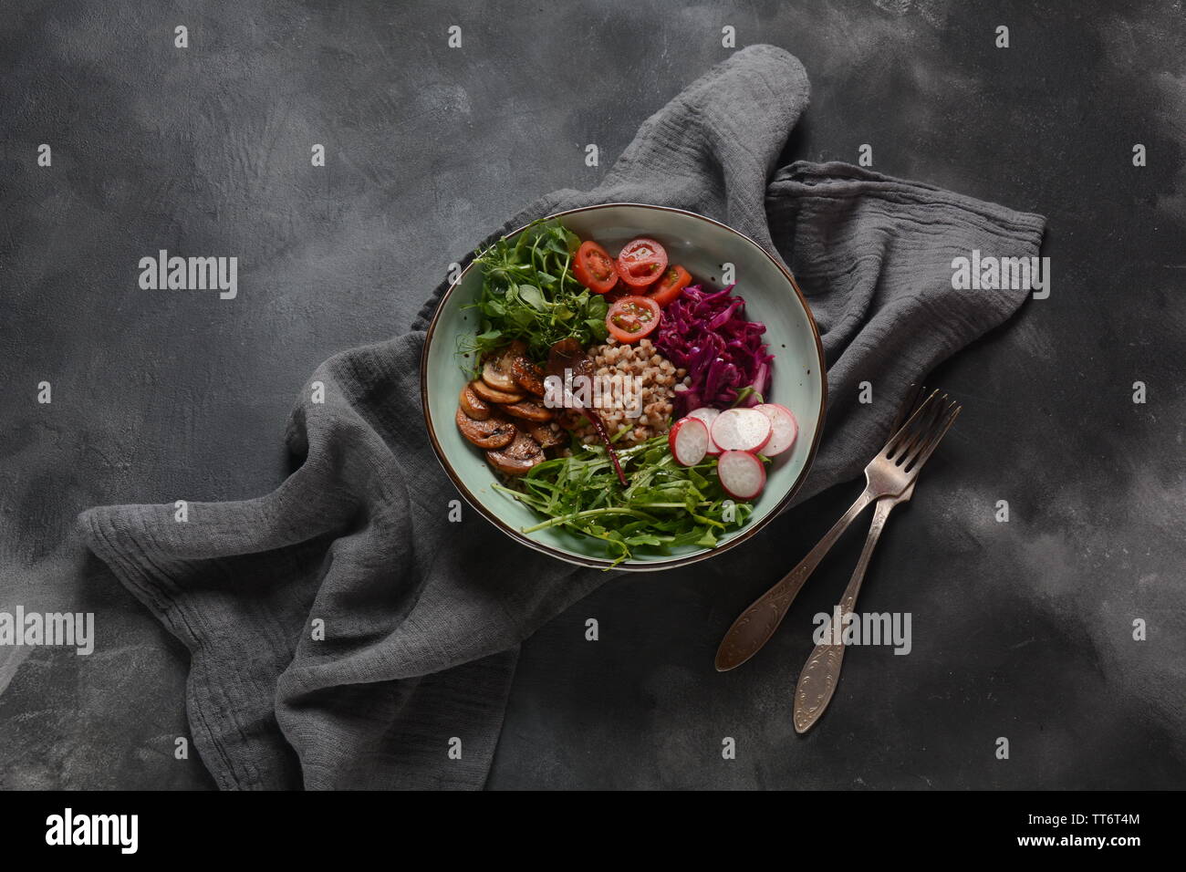 Buddha bowl with red cabbage, tomatoes, radish, arugula beet leaves, pea shoots, buckwheat
