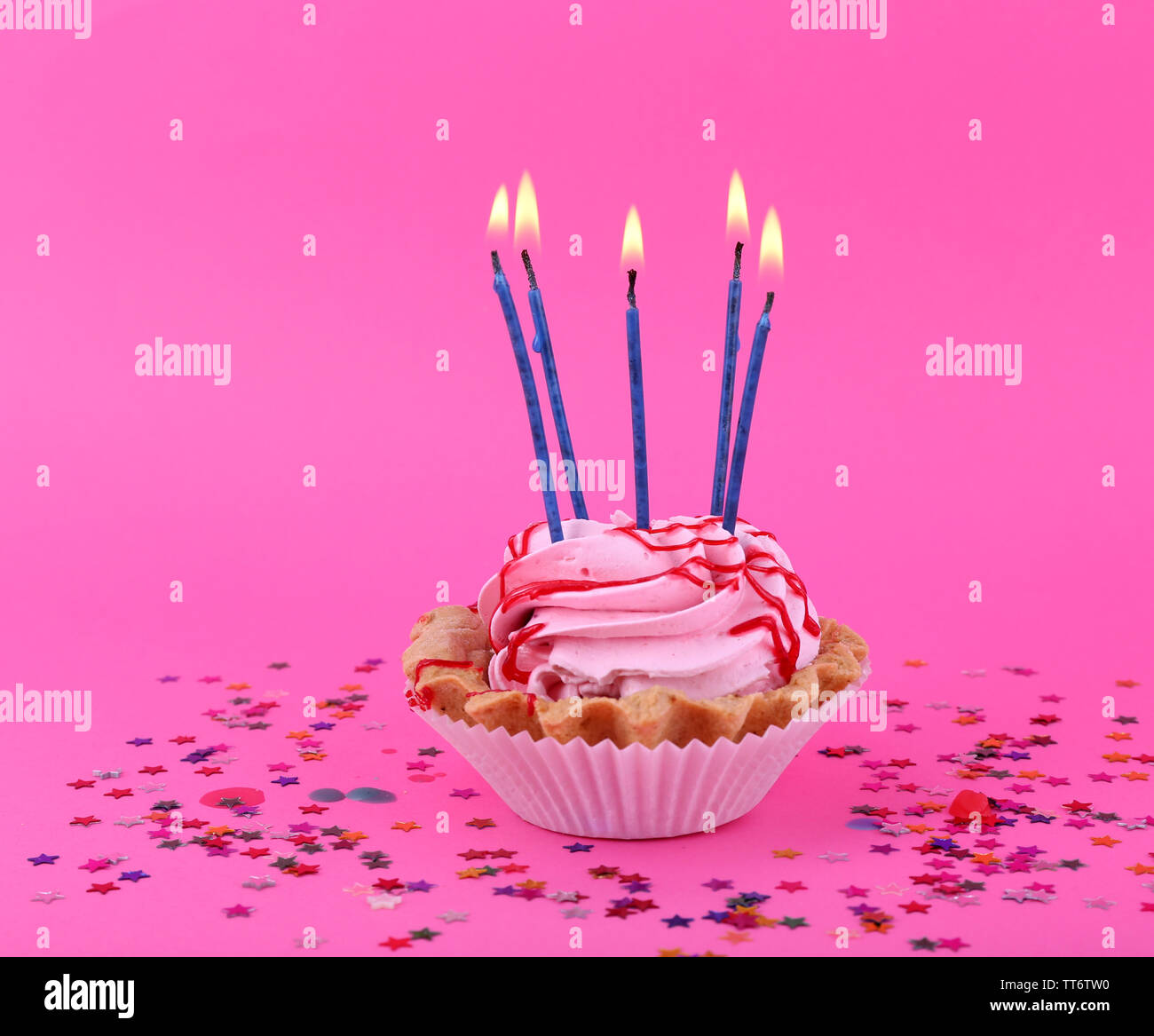 Birthday cup cake with candles and colorful stars on pink background ...