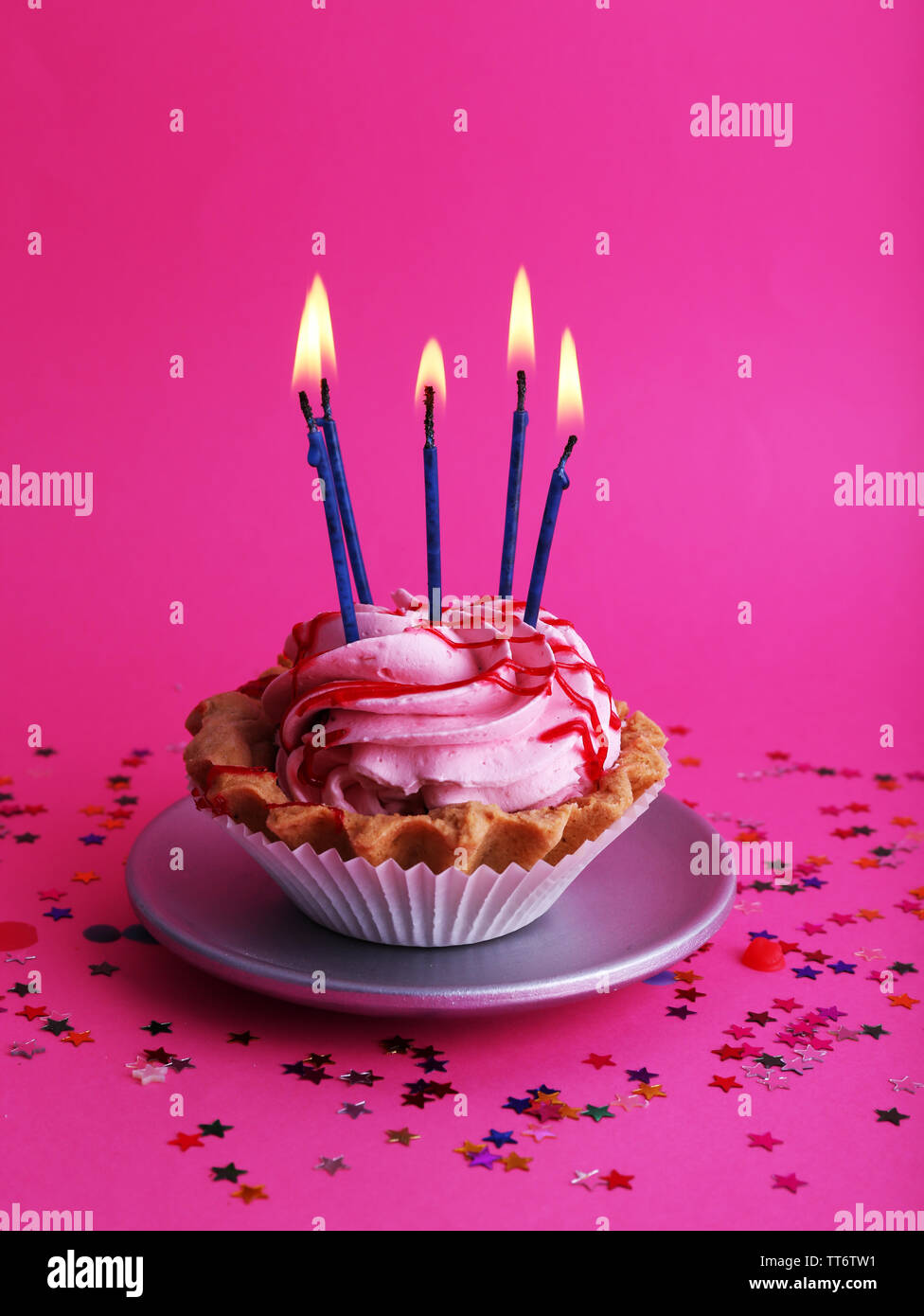 Birthday cup cake with candles and colorful stars on pink background ...