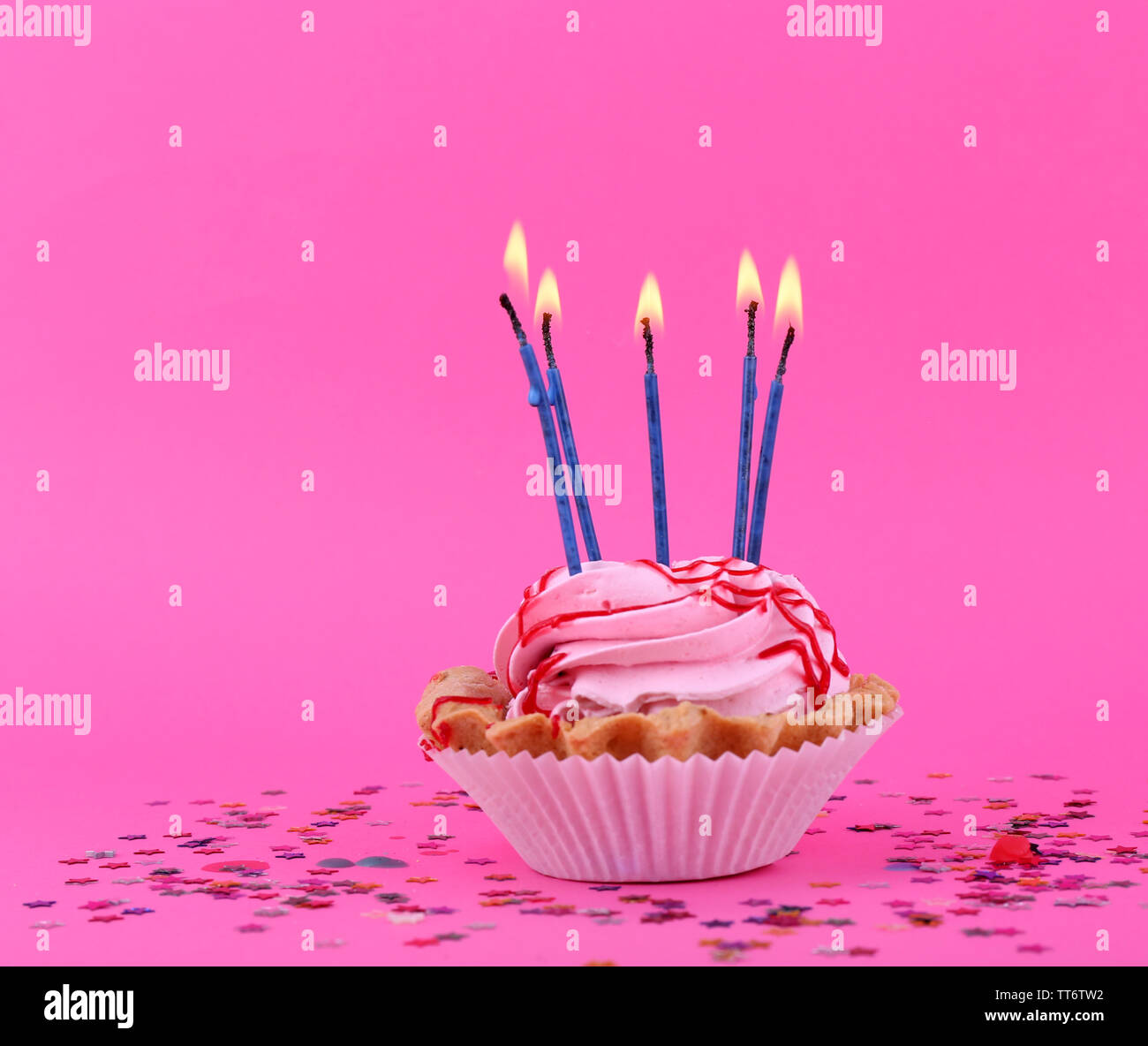 Birthday cup cake with candles and colorful stars on pink background ...