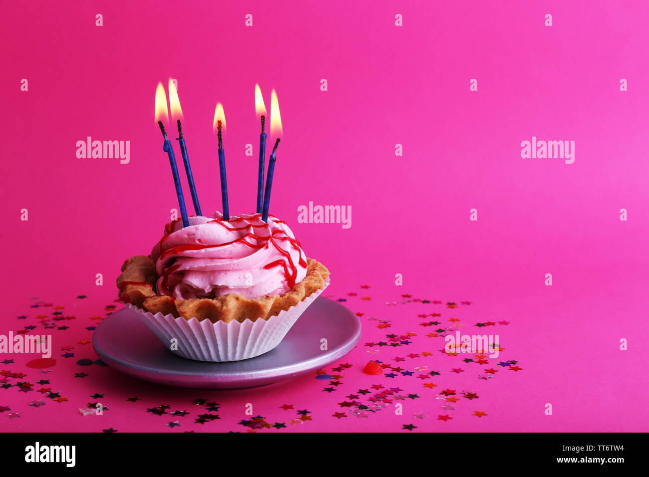 Birthday cup cake with candles and colorful stars on pink background ...